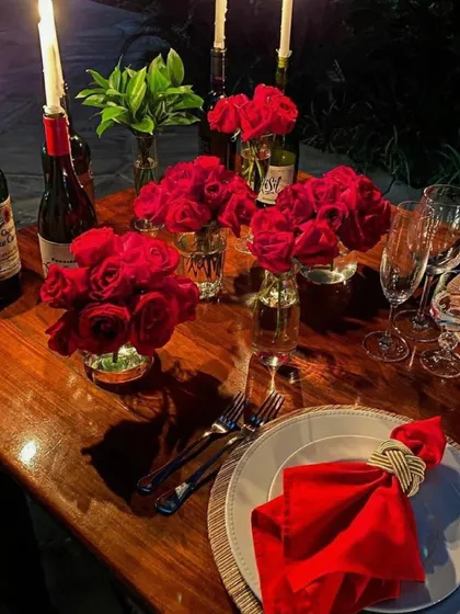 Another angle of a romantic dinner setup. I used wine bottles as unique candle holders and arranged small bouquets of red roses to create a passionate and intimate dining experience.