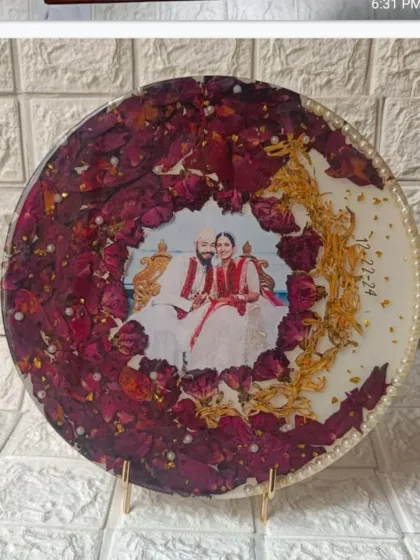 This round plaque showcases a wreath of preserved red rose petals and golden kaleere accents. The couple's photo is placed in the center, creating a classic and romantic wedding keepsake.