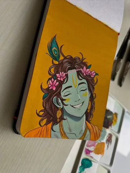 Another angle of my Krishna painting, showing the sketchbook and my paint palette nearby.