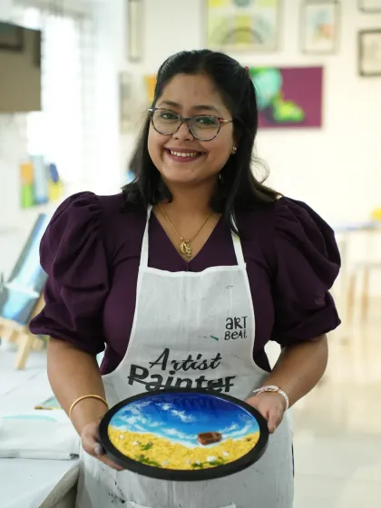 A participant proudly holds up her completed resin beach art, featuring realistic waves, a sandy shore, and a tiny boat. It’s amazing what you can create in just one session, even with no prior experience.