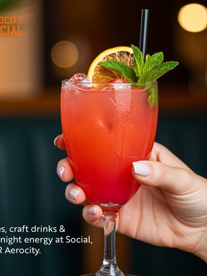 A hand holds a vibrant red cocktail at Aerocity Social. This image embodies the lively vibes, craft drinks, and late-night energy that make Social a go-to spot for a fun night out.