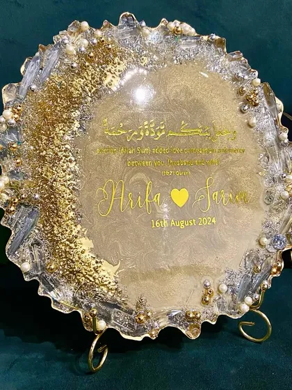 A beautiful resin engagement plaque designed to celebrate a new union. This piece features the couple's names, their special date, and a Quranic verse, all set in a shimmering gold and pearl design with a geode-style edge.
