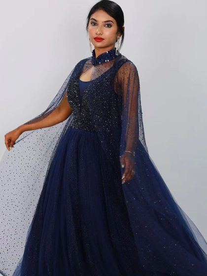 Another powerful pose in the navy blue caped gown, highlighting the high-neck design of the cape and the intricate beading on the bodice.