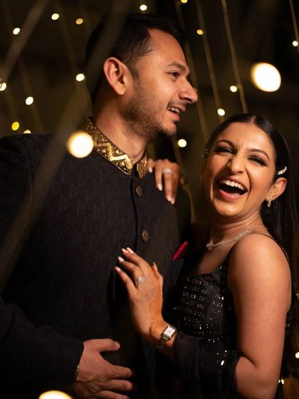 A moment of shared laughter during a pre-wedding shoot, the fairy lights creating a warm and intimate atmosphere.