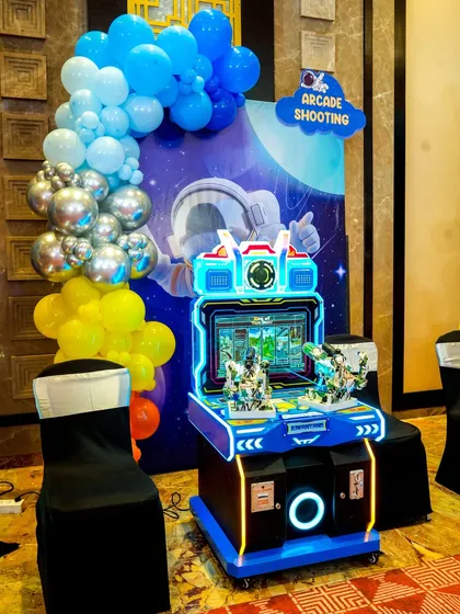 An arcade shooting game with two guns, allowing for two-player action. The machine is lit up and ready for play at a space-themed event.