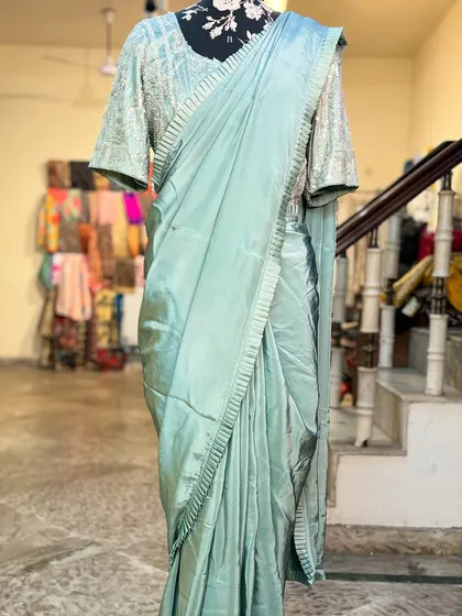 The simple pleated border of the 'MANOHARI' saree complements the heavily embellished blouse and jacket perfectly.