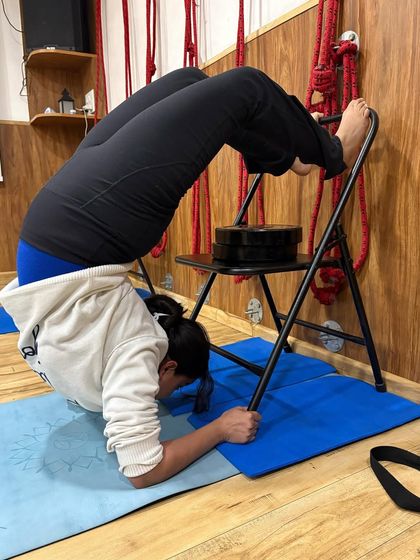 Even in a simple hoodie, this student finds deep release. The chair and weight provide the stability needed to relax into this forearm backbend and focus on the breath.