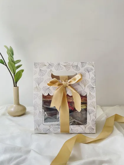 Our Mini Rakhi Hamper is perfect for a sweet and simple gesture. Packaged in a lovely window box, it contains a selection of our Regal Riches, choco almonds, and wheat cookies, complete with a Rakhi.