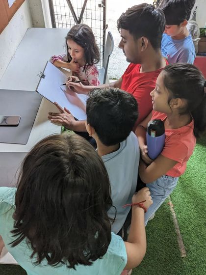 A close-up of the demonstration. The children are eager to see how the drawing comes to life, step by step.