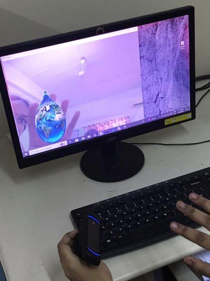 A student interacts with an augmented reality program during our AI workshop. This project involves using a camera and code to overlay digital objects, like the spinning Earth, onto the real world.