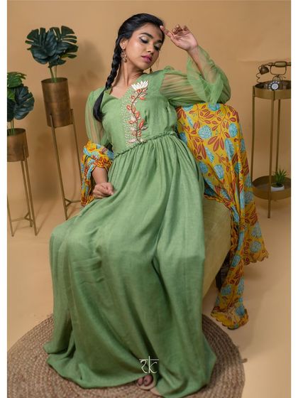 A pickle green floor-length dress that is both elegant and earthy. The single embroidered floral motif on the bodice adds a touch of artisanal charm.