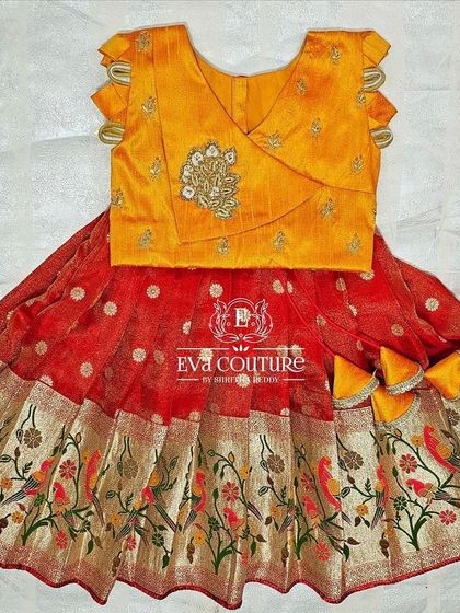 A newborn-sized lehenga with a Paithani-style bird print border. The yellow blouse has a modern wrap-style design.