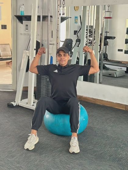 Flexing while seated on a stability ball. It shows that even a simple pose requires core engagement to maintain balance.