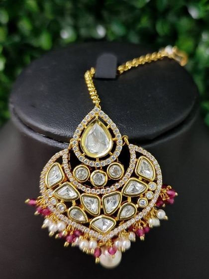 A similar design with red bead drops, this kundan maang tikka is perfect for a traditional red lehenga.