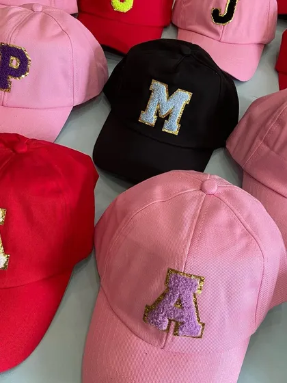 Another view of our colorful custom caps, showing how different initials look on various cap colors like pink, red, and black. A perfect personalized accessory for any child.