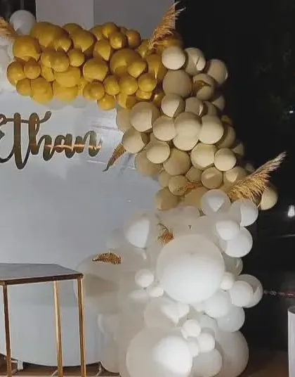 An elegant baptism or christening celebration for Ethan. The all-white setup is accented with gold balloons and dried pampas grass for a sophisticated and serene look.