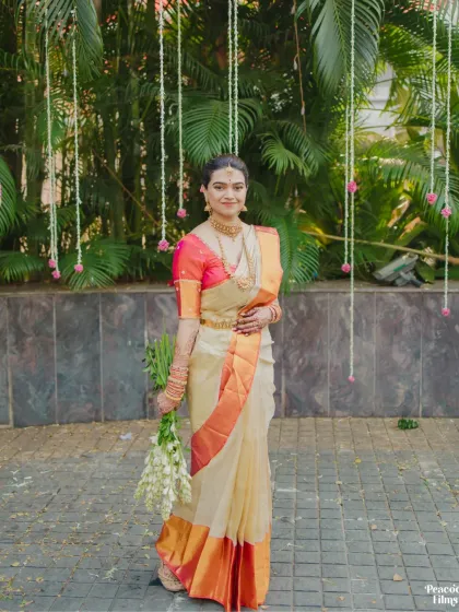 A portrait of South Indian bridal elegance. The bride, in her beautiful silk saree, holds a bouquet of white flowers, her expression serene and graceful.