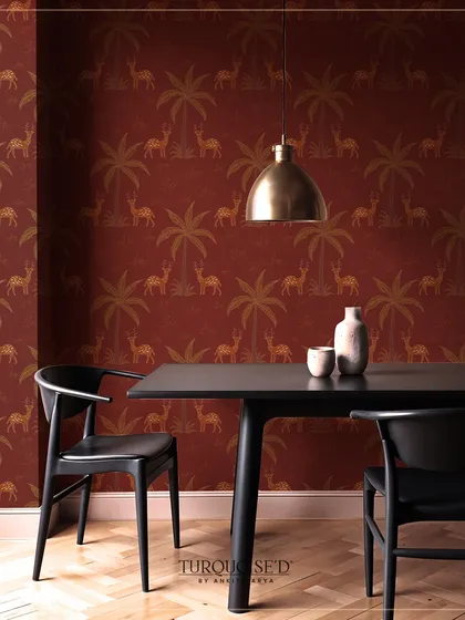 The Sundarban Boota wallpaper in a deep red, featuring a repeating pattern of deer and palm trees. This design brings a warm, earthy, and narrative quality to this modern dining space.
