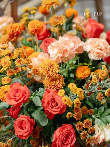 A close-up of the vibrant floral arrangements for the Rishikesh Haldi. A mix of orange roses and marigolds creates a rich, traditional color palette that feels both festive and elegant.