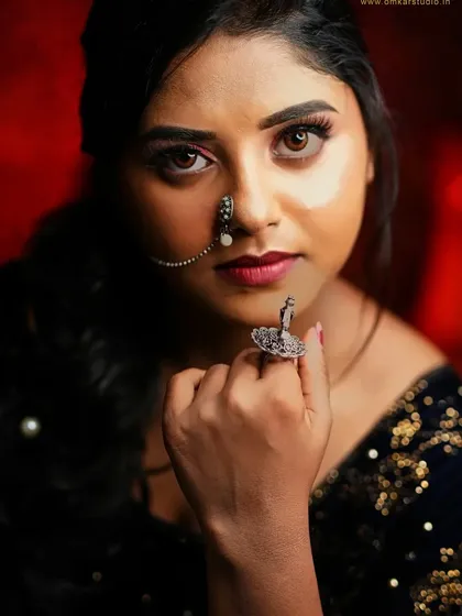 A portrait is powerful when it connects with the viewer. This close-up studio shot uses a rich, warm background and focused lighting to draw attention to the subject's direct gaze and the intricate details of her traditional nose ring, creating an image that is both bold and intimate.