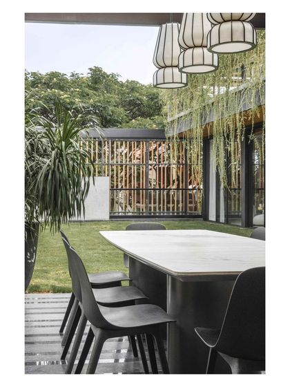 Delicate, sculptural pendant lamps hang above the outdoor dining table, adding an artistic touch to the al fresco setting.