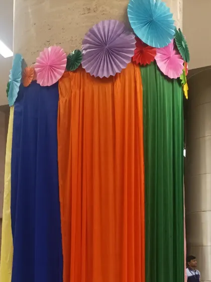 We believe in decorating every part of the office! Here, we've wrapped an office pillar in colourful drapes and topped it with paper craft fans to continue the Holi theme throughout the space.
