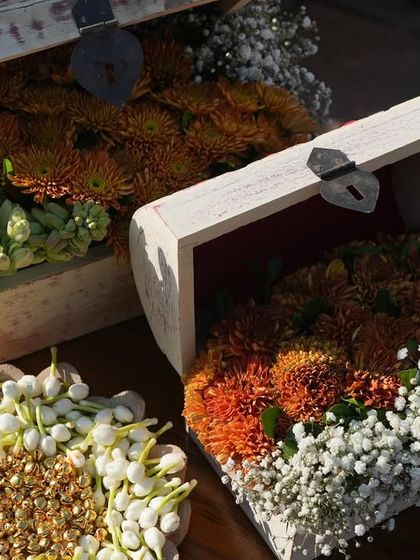 Treasure chests filled with vibrant orange chrysanthemums and delicate tuberoses, used as unique decor pieces along the aisle.