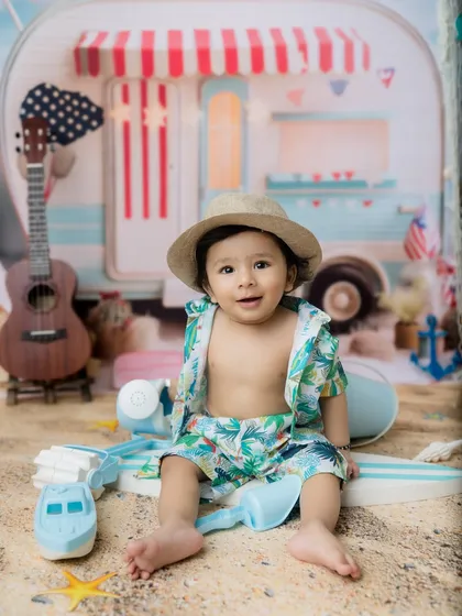 This little beach bum is ready for his close-up in a cute hat and tropical print outfit.