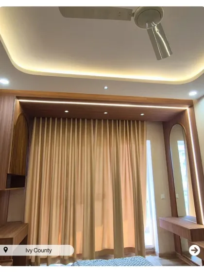 This bedroom features a beautiful archway created with wood paneling, framing the window and creating a cozy nook with integrated study and vanity tables.