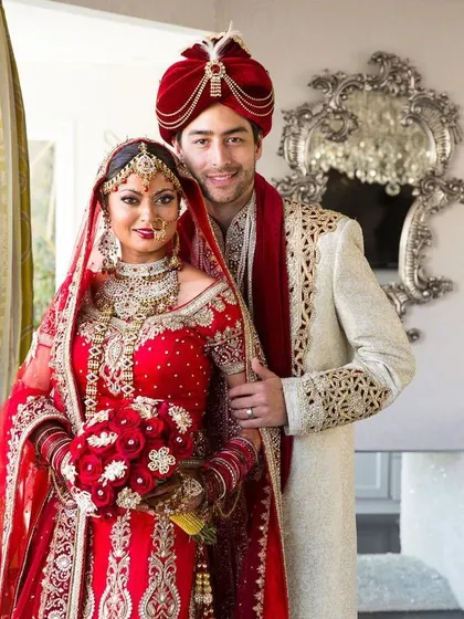For a grand bridal look, this all-red lehenga with heavy gold embroidery is a showstopper. We've paired it with a sophisticated cream sherwani for the groom that has delicate gold embroidery, creating a balanced and royal couple look.