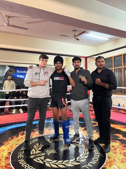 A student and his coaches pose for a photo after his victory, celebrating the teamwork that led to this moment.