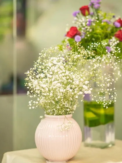 A simple yet beautiful detail of a baby's breath bouquet in a pink ceramic vase, perfect for adding a soft touch to any celebration.