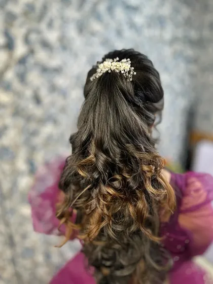A soft and romantic ponytail with curls, perfect for a reception or party. The look is finished with a simple pearl hair accessory.