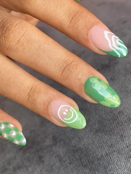 A close-up of the green-themed nails, showing a fun smiley face and abstract patterns.