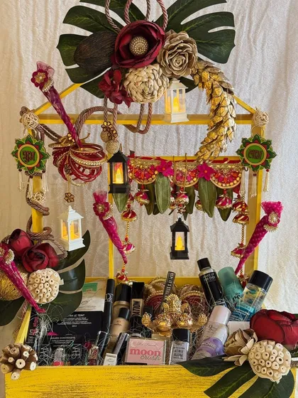 A vibrant and eclectic Diwali hamper for a makeup lover. This yellow-tiered stand is filled with cosmetics and decorated with traditional Indian hangings and miniature lanterns.