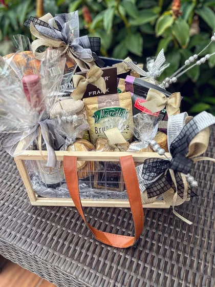 This fully assembled goodie basket for a corporate leader features a mix of savory snacks, premium drinks, and sweets. The arrangement in a reusable wooden crate with leather handles combines rustic charm with a polished, professional look.