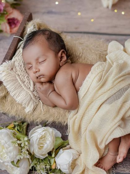 A sleeping angel. I love the simplicity of this setup, with the baby nestled in a rustic bed surrounded by soft white flowers.
