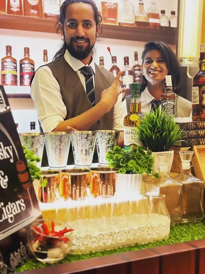 A welcoming view of the Whisky and Cigar station. My bartenders are ready to serve, with a custom chalkboard sign clearly announcing the theme, complemented by elegant glassware and copper mugs.
