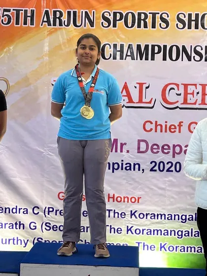 A gold medalist from the Arjun Sports Shooting Championship, proudly standing on the podium.