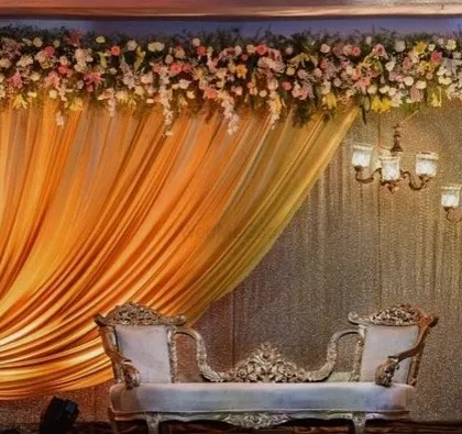 An elegant and classic stage design for a reception. I used a golden fabric drape on one side, complemented by a thick floral border on top and ornate chandeliers on the other side for a royal look.