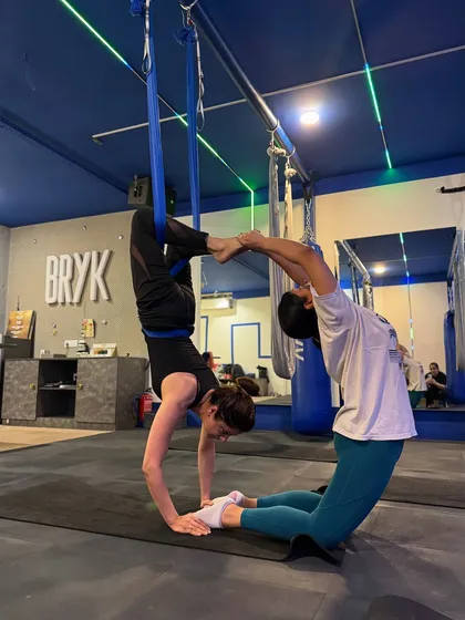Partner work is a great way to build trust and strength. Here, two members create a beautiful, balanced shape, supporting each other through the pose.