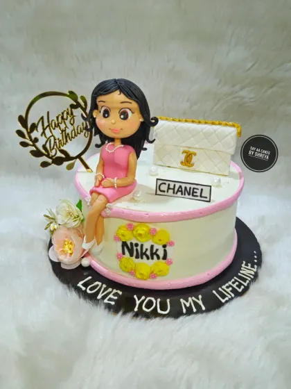 A cake as elegant and timeless as the woman it was for. This design features a custom figurine of the birthday girl sitting next to her favorite Chanel bag, surrounded by delicate flowers.