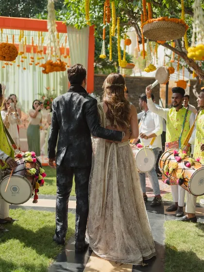 A grand entrance for the couple at their Mehendi, flanked by dhol players. This creates a high-energy, traditional welcome that gets everyone in the mood to celebrate.