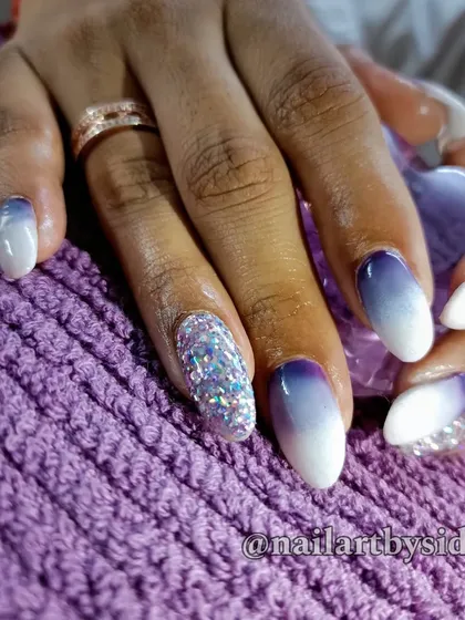 A stunning purple-to-white ombre on almond-shaped nails, with a full accent nail of sparkling pixie dust crystals.