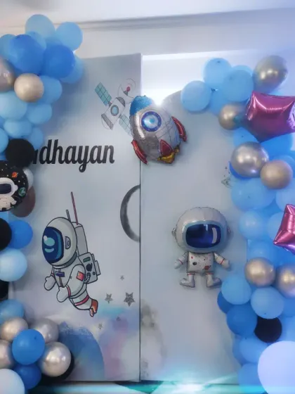 The complete space-themed setup for Adhayan's party. The decor includes a crescent moon, rocket, and astronaut balloons to create an intergalactic adventure.