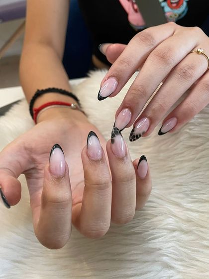 A modern and edgy look with black French tips and a subtle snake print accent nail on long almond extensions.