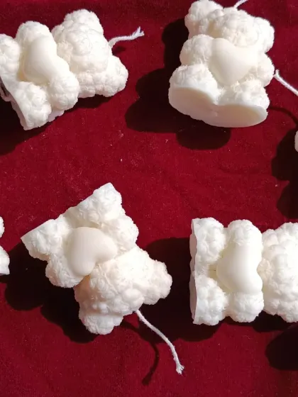 These are my smaller, standalone teddy bear pillar candles, shown scattered on a red background.