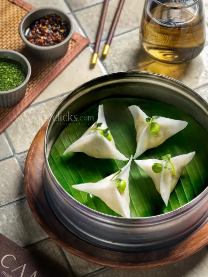 Triangle-shaped dim sum on a banana leaf, shot for Camo, Noida. The composition is clean and minimalist.