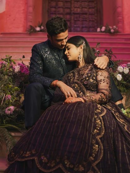 A romantic portrait of a couple seated on steps adorned with flowers, sharing a tender embrace.