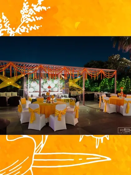 The same Haldi setup at night, where the warm lighting and fairy lights in the background add a magical glow to the festive yellow and orange decor.